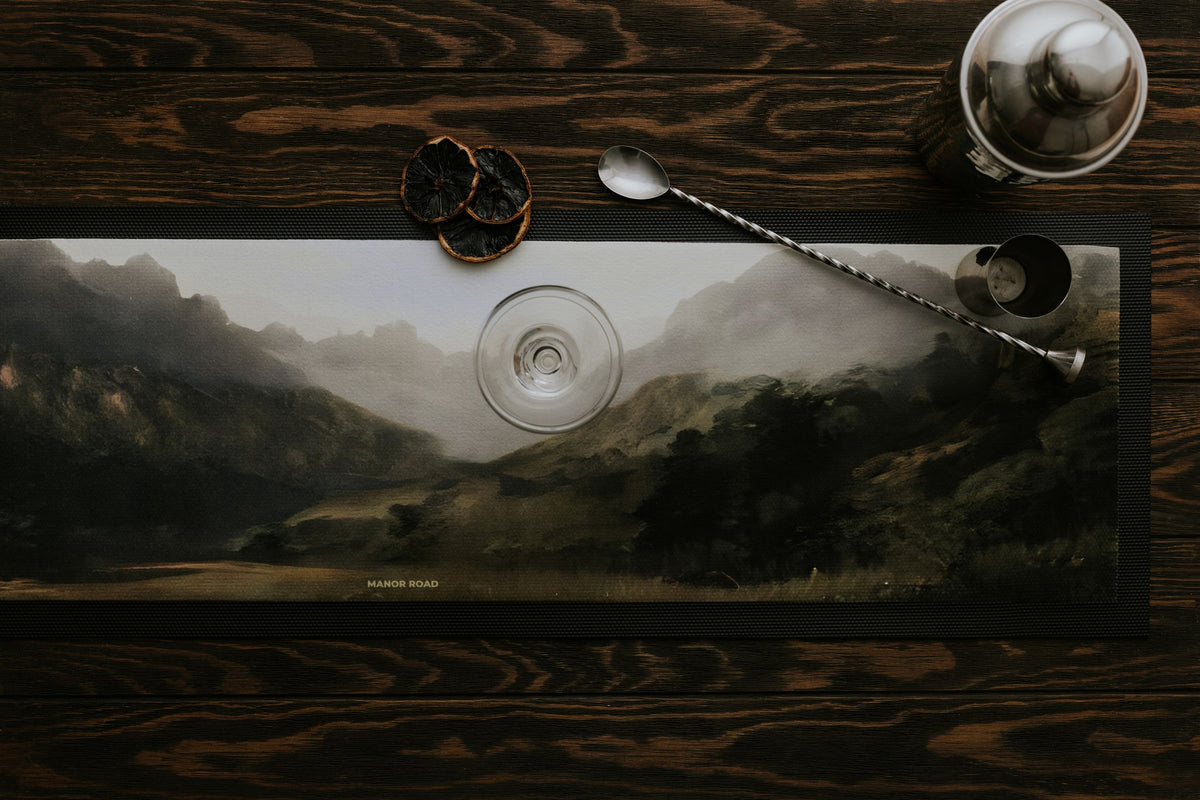 Large rubber backed bar mat by Manor Road with a landscape mountain image. With cocktail shaker and stirrer. 