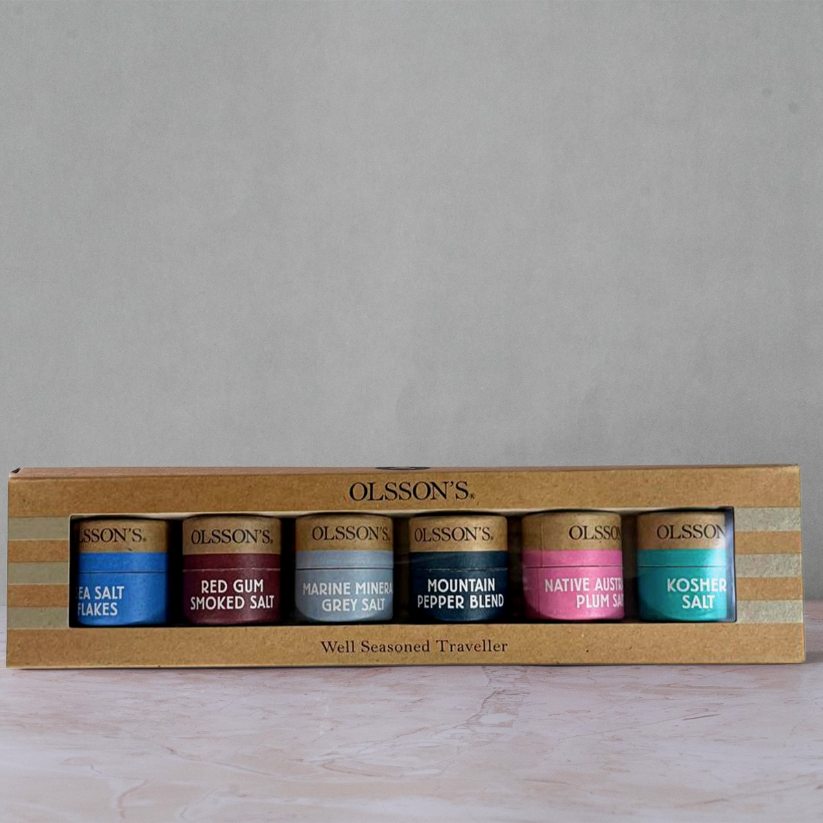 Olsson's Well Seasoned Traveller salt set in a wooden box, showing five different salt flavors: Sea Salt, Red Clump Spiced Salt, Marine Pepper Blend, Mountain Pepper Blend, Native Agate Pepper, and Kosher Salt.