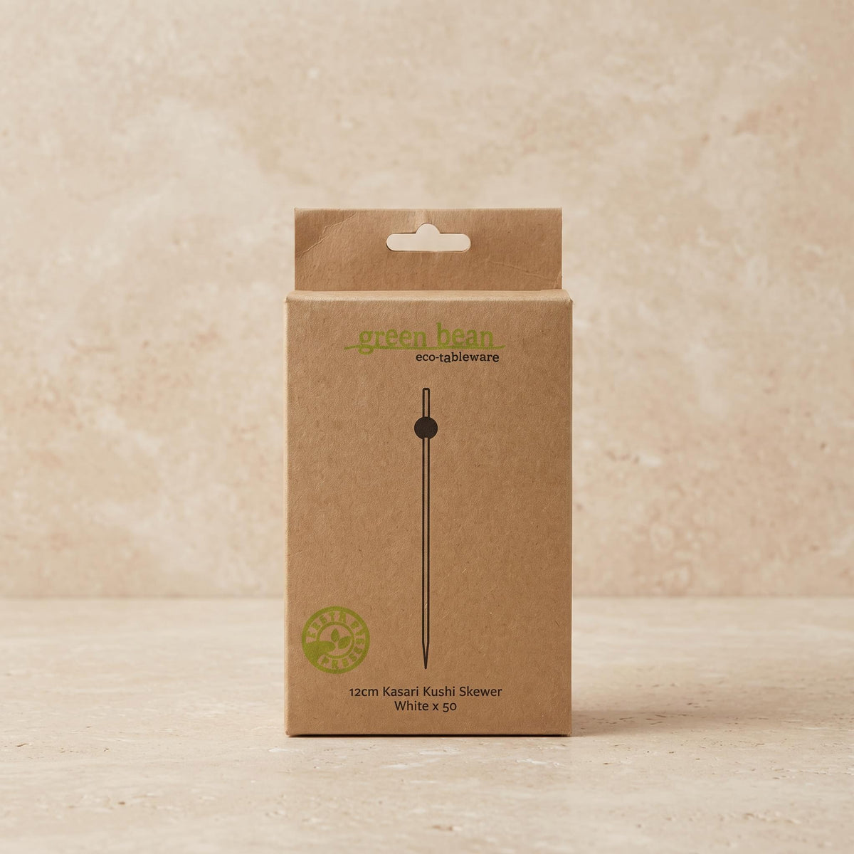 A brown kraft paper box for a 12cm Kasari kushi skewer by Green Bean Eco-Blowstacks, standing upright on a light beige textured surface.