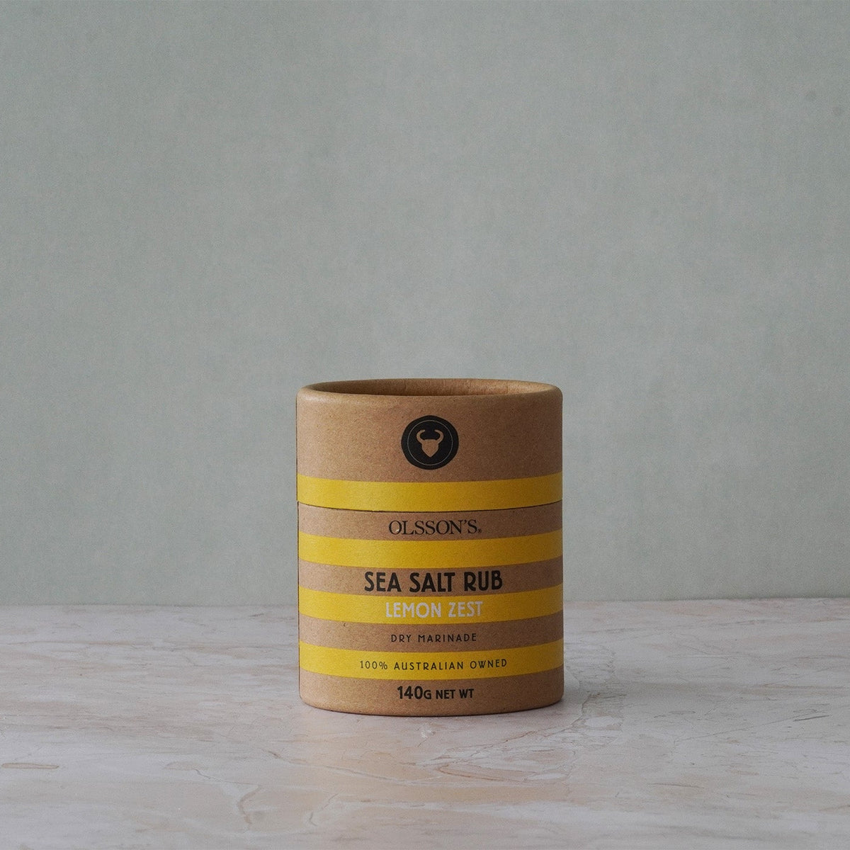 Cylindrical container of sea salt rub with striped design on a gray background