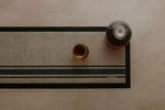 Rubber backed bar mat with linen woven look print. Glass bottle and drinking glass on the bar mat at a drinks station to catch spills. 