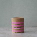 Olsson's Native Australian Ruby Salt in a kraft paper cylinder container with pink stripes, set on a light marble surface against a muted gray-green background.