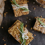 Cracker squares with rosemary tied with string on a dark surface