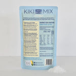 A light blue pouch of Kiki Seed Cracker Mix gourmet seed crackers, shown with a small pile of white cracker pieces in the foreground against a light gray background.