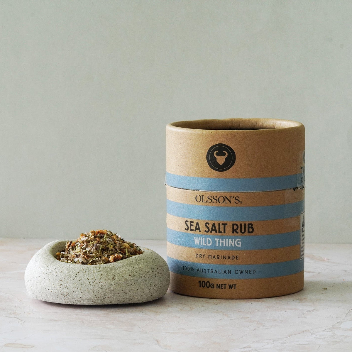 Ollsson's Sea Salt Rub container with a small bowl of salt on a light wooden surface.
